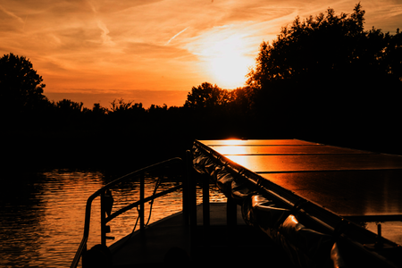 De punt van de rondvaartboot met op de achtergrond de ondergaande zon
