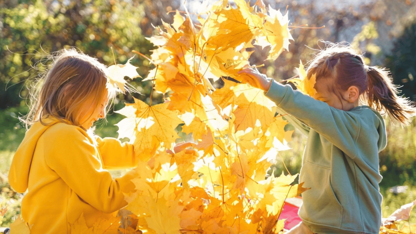 Kinderen spelen met gevallen herfstblaadjes