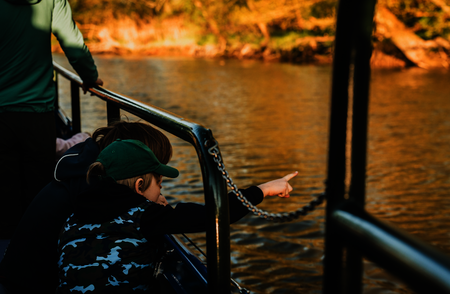 Een jongetje op de boot wijst naar iets (een bever?) in het water