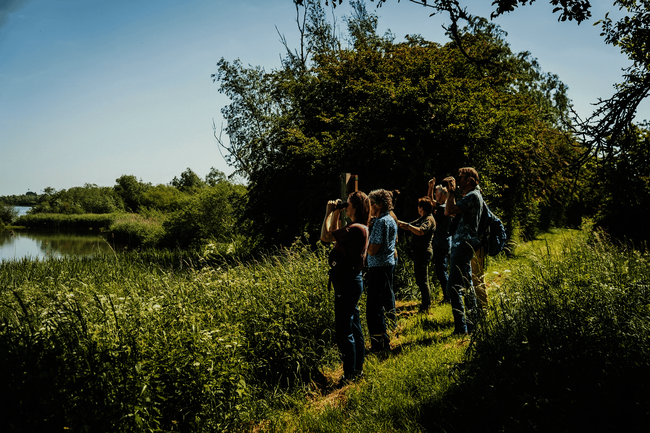 Wandelaars kijken in de Biesbosch naar het water
