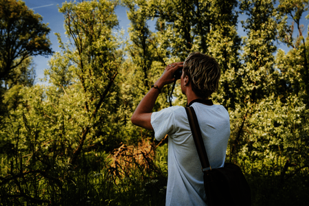 Een wandelaar in de ruige natuur tuurt door een verrekijker naar de lucht